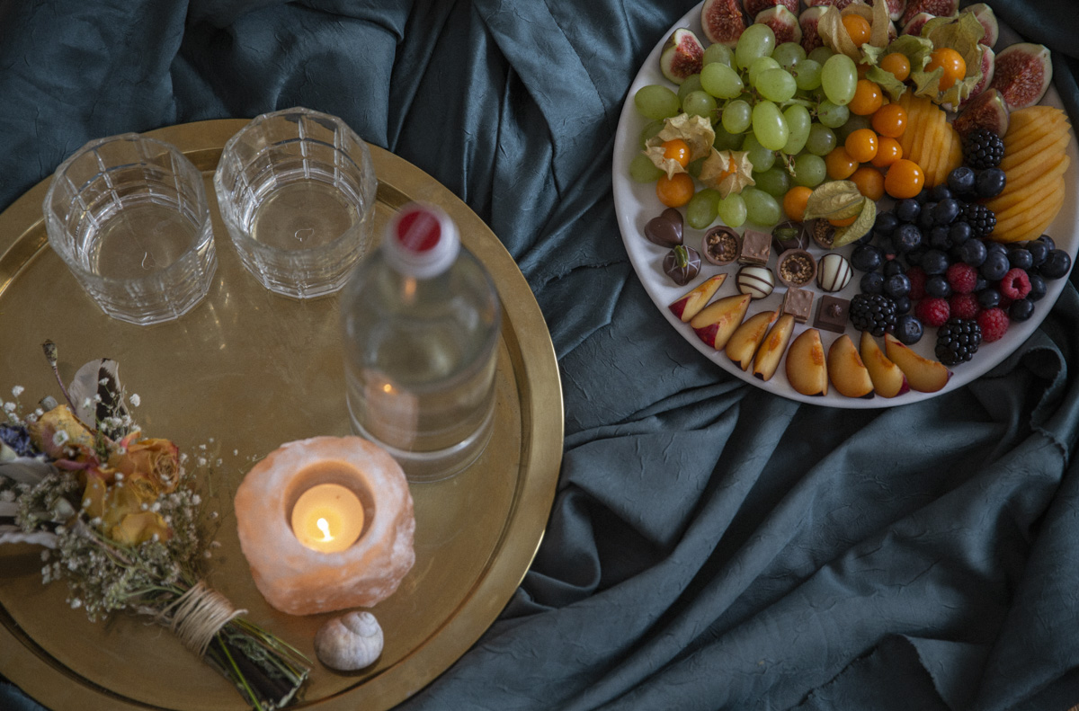 Früchte und Kerzen auf Schalen auf einer blauen Decke
