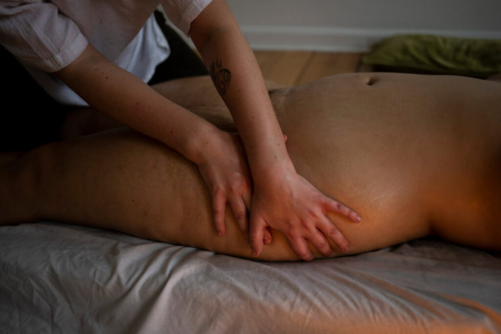 Massage der Hüften von nackter, liegender Person durch eine andere Person